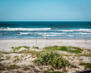 People with surfboards walking down the beach by the waves near Silver Sands in New Smyrna Beach.